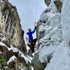 person in blue jacket ice climbing